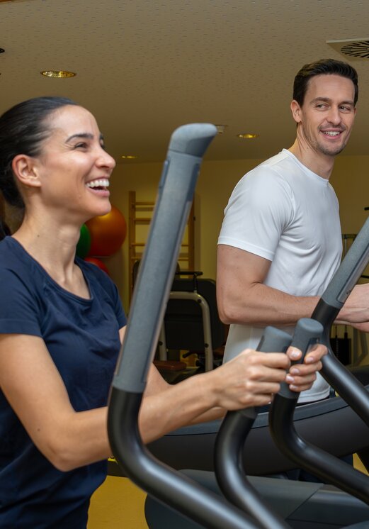 Frau und Mann trainieren auf Laufbändern im Fitnessraum