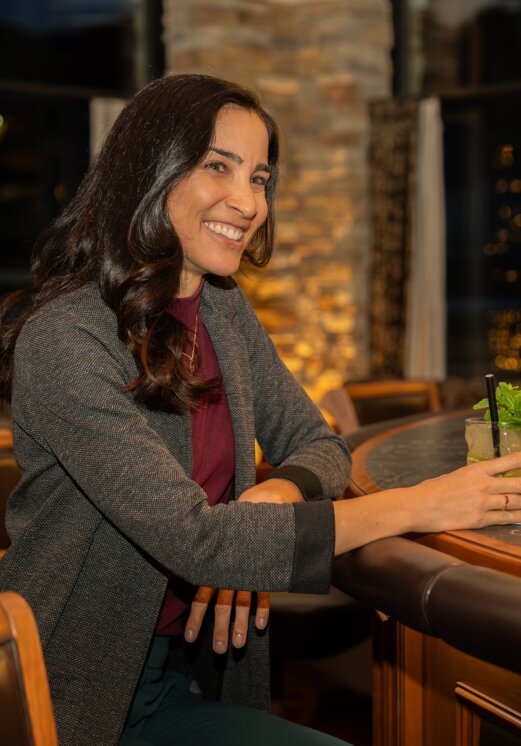 Frau lächelt mit Cocktail an Hotelbar