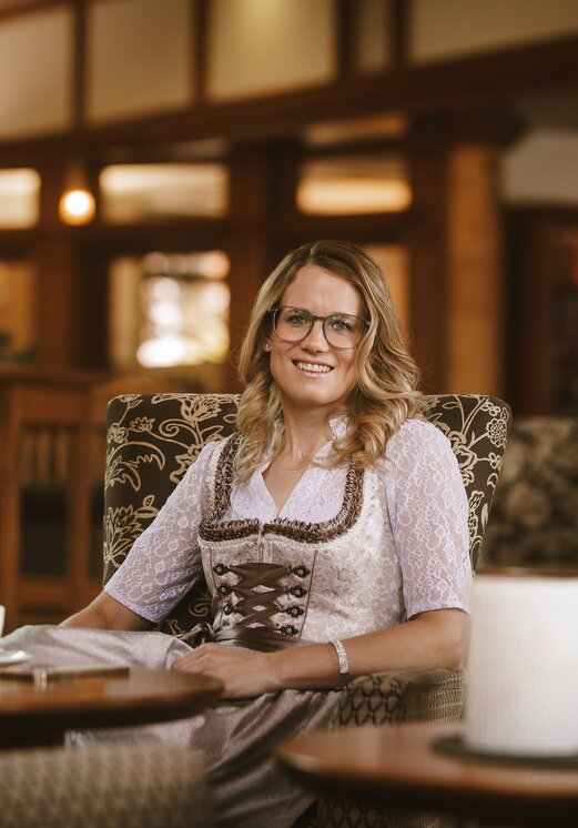 Frau im Dirndl sitzt mit Kaffee im Hotel Tyrol am Haldensee