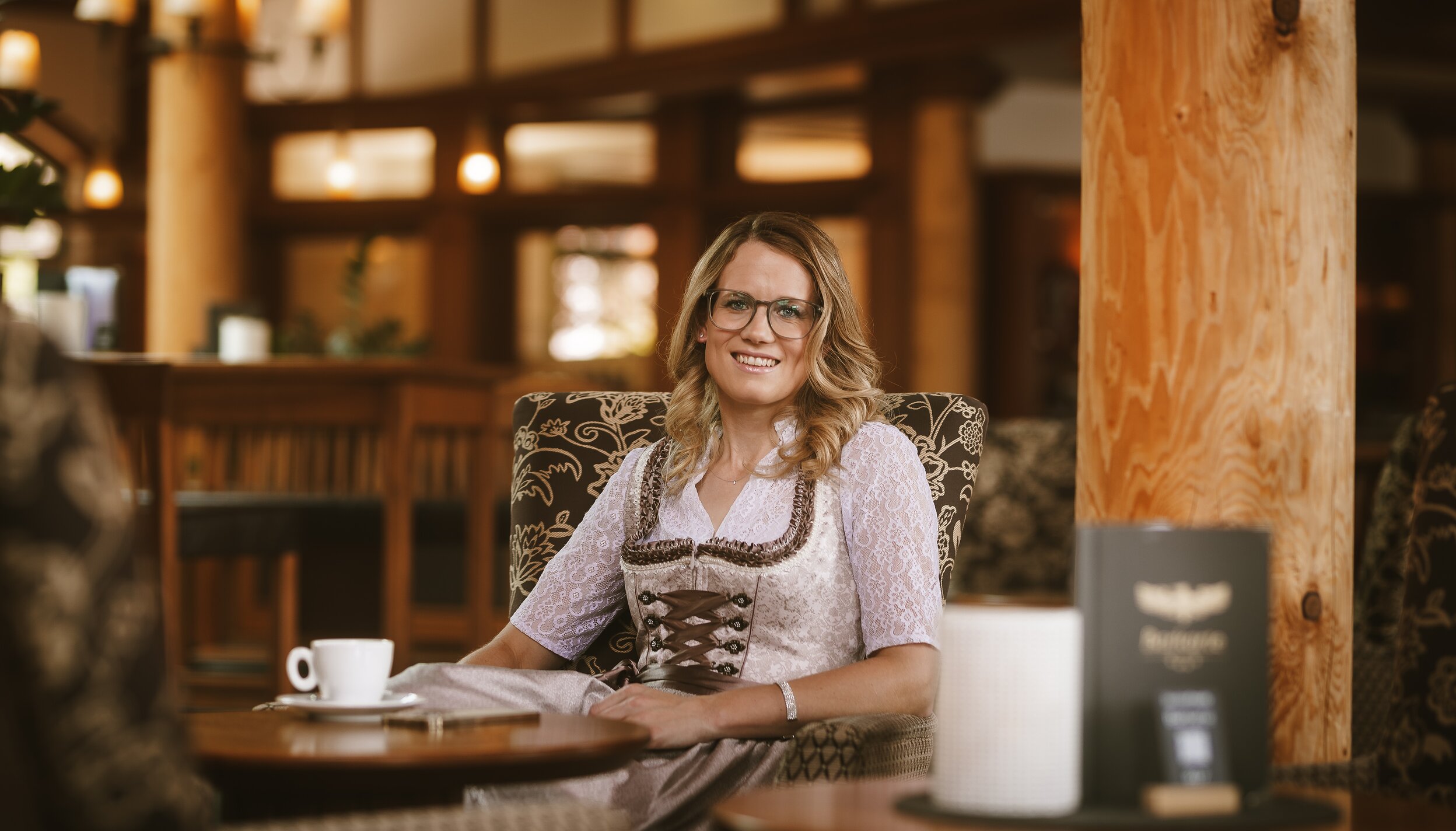 Frau im Dirndl sitzt mit Kaffee im Hotel Tyrol am Haldensee