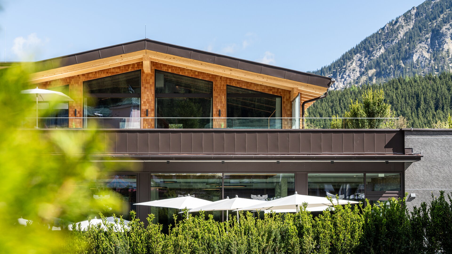 Hotel Tyrol am Haldensee, Außenansicht mit Terrasse und Berg im Hintergrund