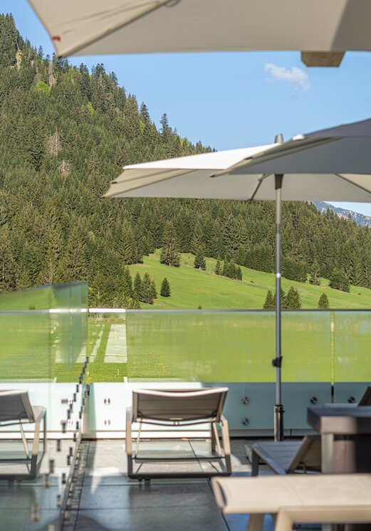 Hotel Tyrol: Terrasse mit Liegen und Sonnenschirmen vor Bergkulisse