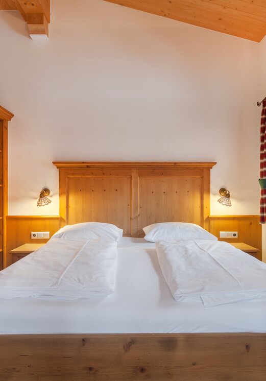 Schlafzimmer mit Doppelbett und Holzmöbeln im Hotel Tyrol am Haldensee