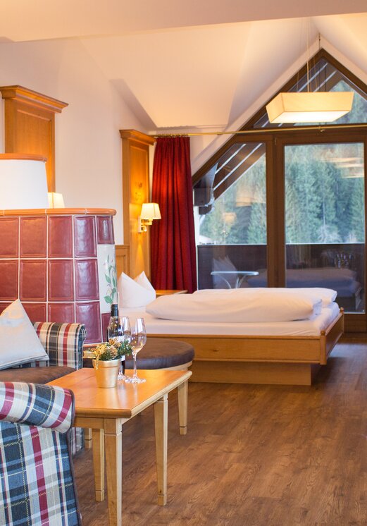 Hotelzimmer mit Kachelofen, Bett und Balkon