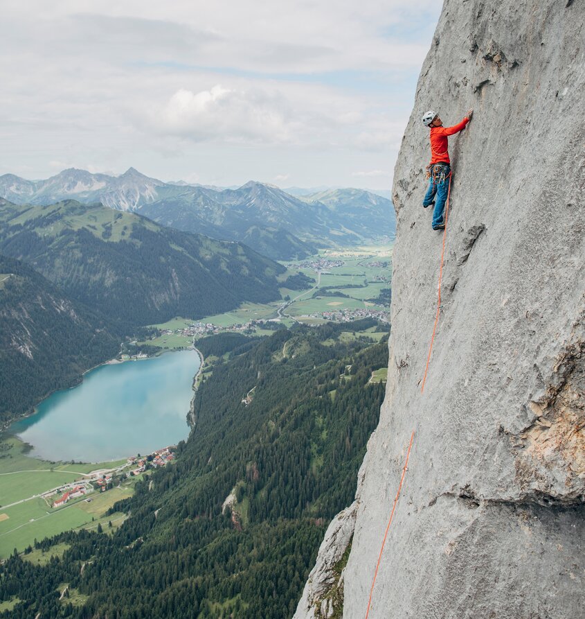 Kletterer an Felswand, Haldensee und Berge im Hintergrund