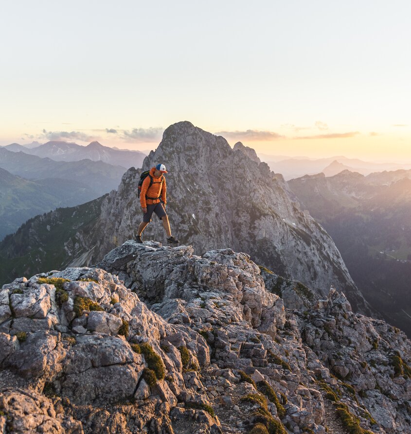 Wanderer auf felsigem Berggipfel bei Sonnenaufgang